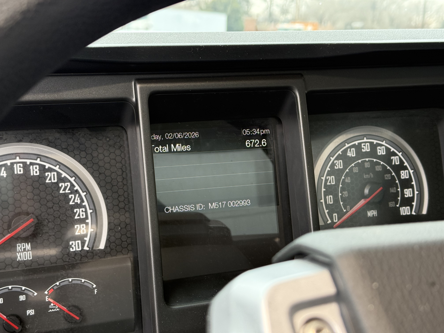 Dashboard display showing total miles 672.6 and chassis ID M517 002993 on Mack GR104F dump truck cab dash.