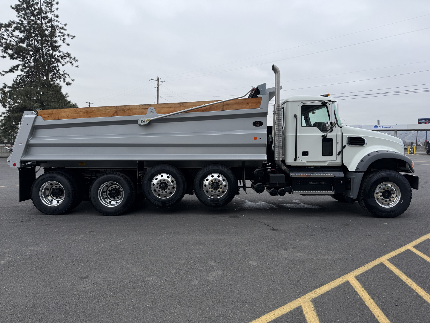 Mack GR104F dump truck in side view showing dump bed, multiple rear axles, white cab, and gray chassis.