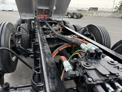 Mack GR104F chassis showing hydraulic lines and control valves, fuel lines, and wiring harness in the truck frame.