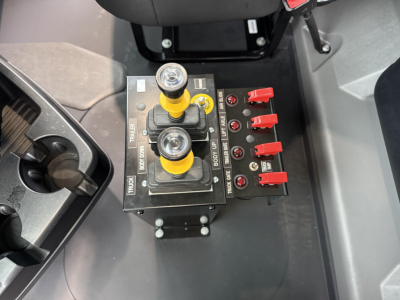 Mack GR104F control panel with hydraulic levers and red toggle switches, viewed from above.