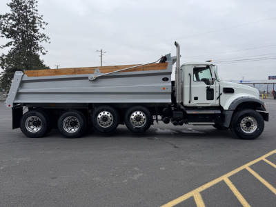 Mack GR104F dump truck in side view showing dump bed, multiple rear axles, white cab, and gray chassis.