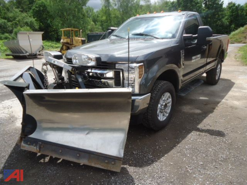 Ford F-250 pickup with a front mount plow in a gravel lot. Front bumper and plow mount visible.