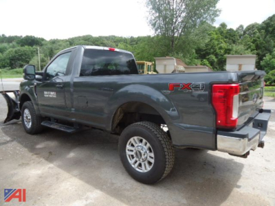 Ford F-250 pickup truck with V-Plow, gray, rear-side view showing FX4 badge, crew cab, alloy wheels, 4x4 stance.