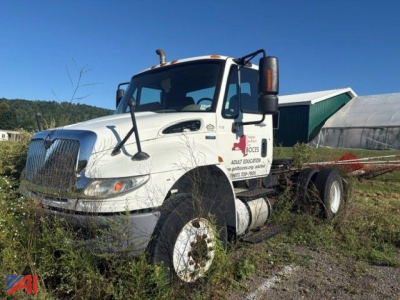 Truck cab exterior with International DuraStar 4400 chassis, white daycab, large grille, side mirrors, and fuel tanks. Visible text on door includes company logo and contact info, but small and not fully legible.
