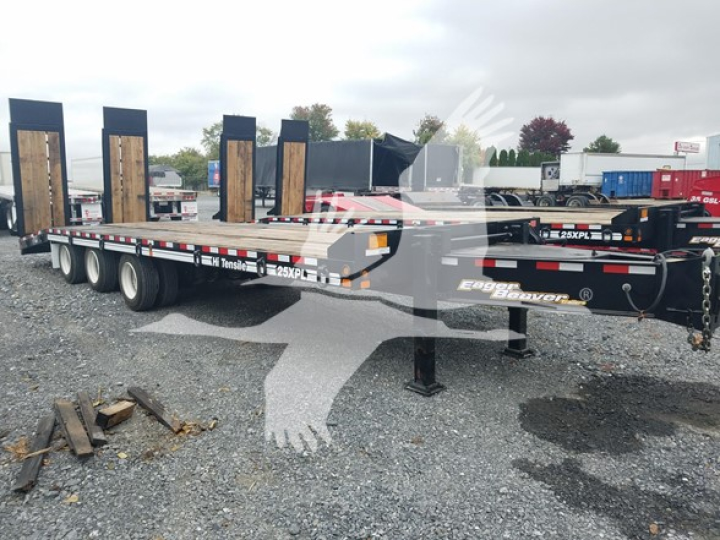 Trailer showing flatbed with dual axle and tall wooden boards on uprights, Eager Beaver 25Xpl branding visible on frame.