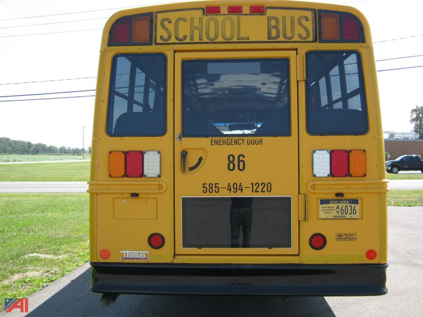 Rear view of a yellow Freightliner C2 school bus showing 'SCHOOL BUS' signage, emergency door, rear lights, bus number 86, phone number, and sticker details.