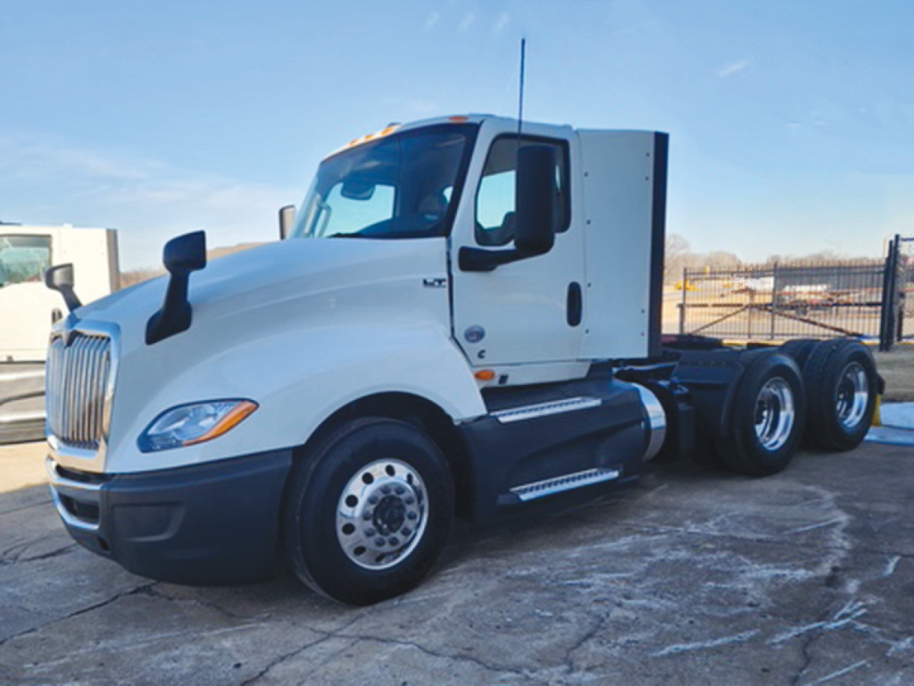 International LT625 truck in a yard, side view showing white cab with black bumper, dual rear axles, and fuel tanks.