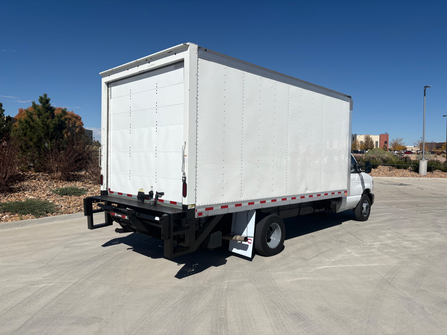Box truck rear 3/4 view showing large white cargo box on Ford E-350 chassis with open rear doors