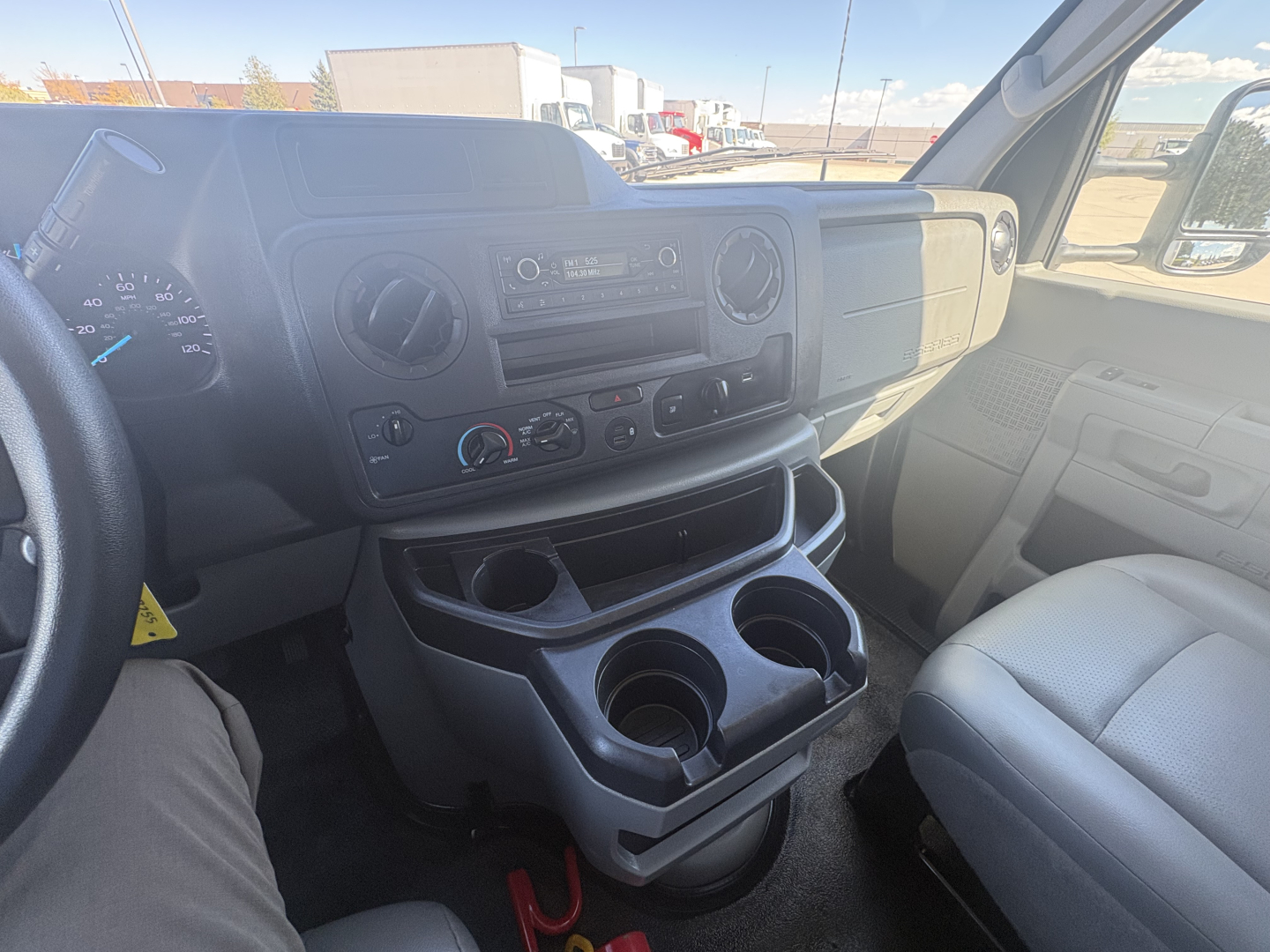 Ford E-350 interior dashboard and center console with steering wheel visible, gear area, cup holders, and climate controls.