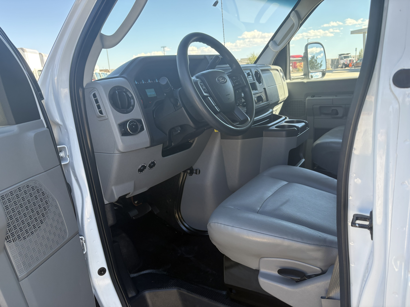 Ford E-Series van/box truck interior showing steering wheel, dashboard, and front seat from open driver door.