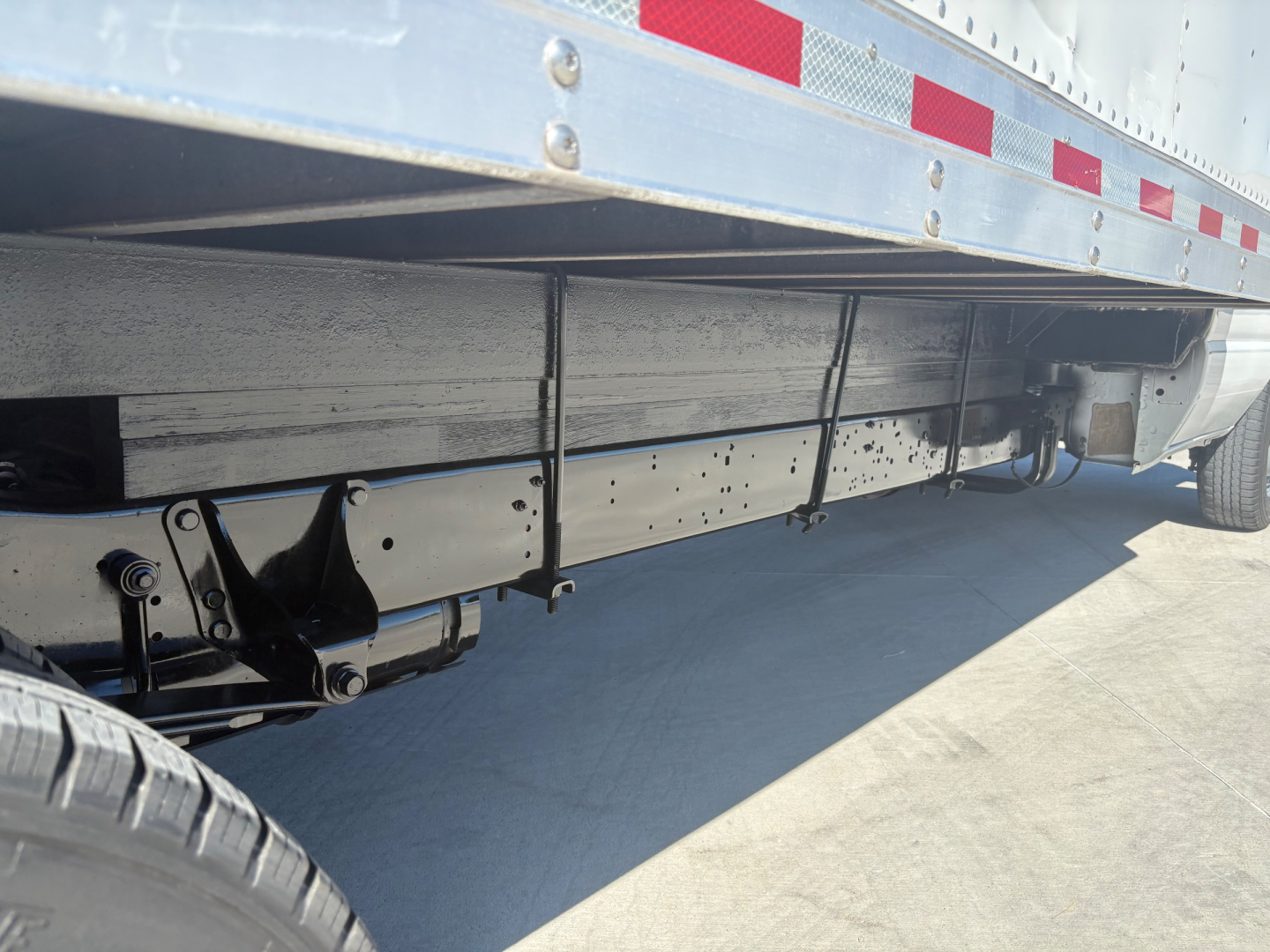 Ford E-350 cargo truck side view showing underbody chassis and wheel, with trailer box above.
