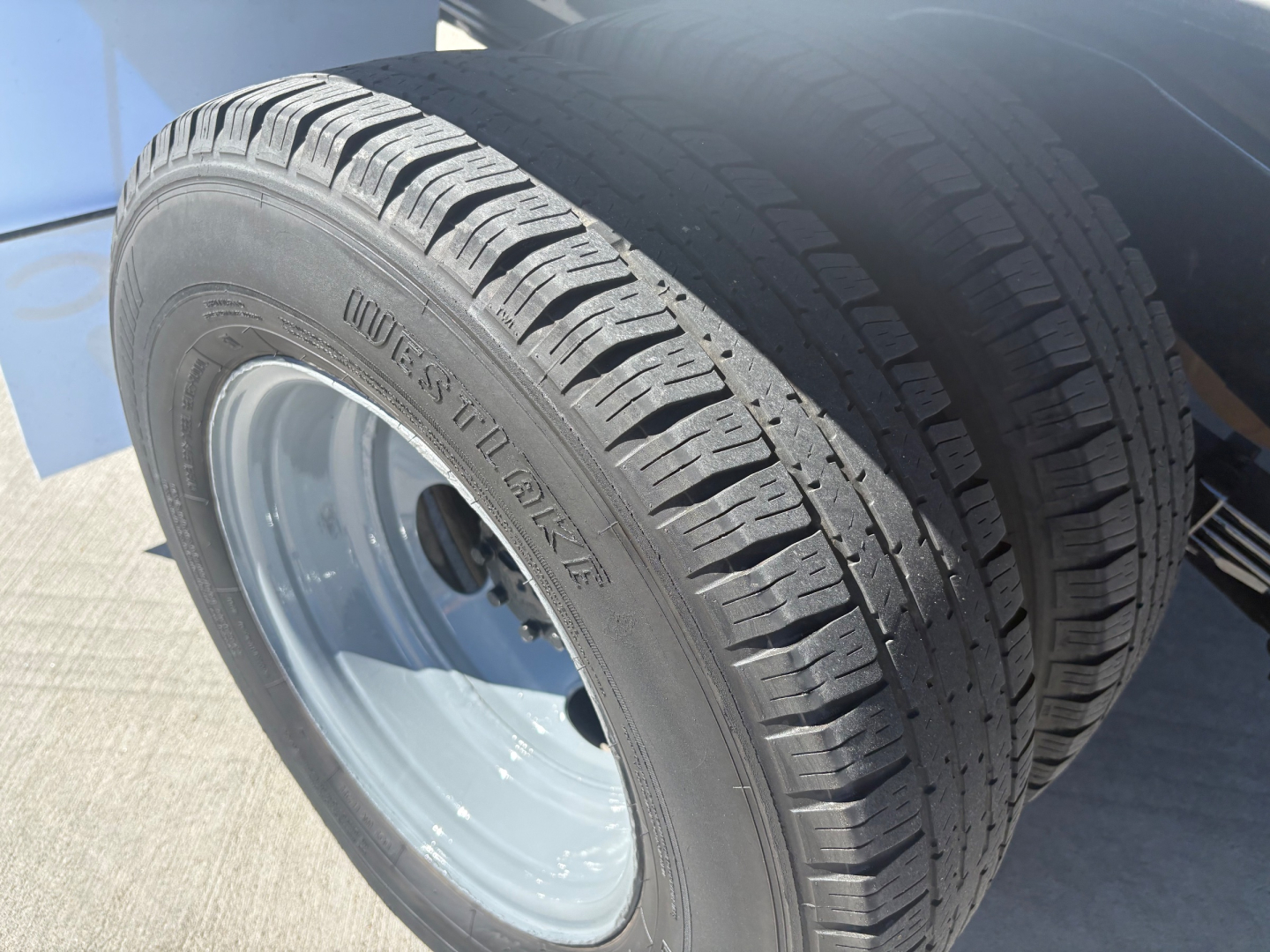 Wheel and tire of a Ford E350 with Goodyear? tire tread visible; steel wheel; portion of front wheel well and body.