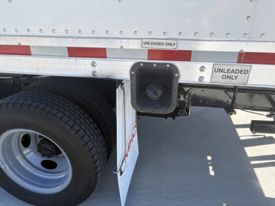 Truck side showing fuel cap access and unleaded labels; wheel and fender visible; stickered reflective tape with UNLEADED ONLY text.