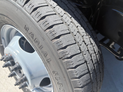 Ford E-350 wheel and tire close-up showing tread pattern, aluminum alloy wheel with lug nuts.