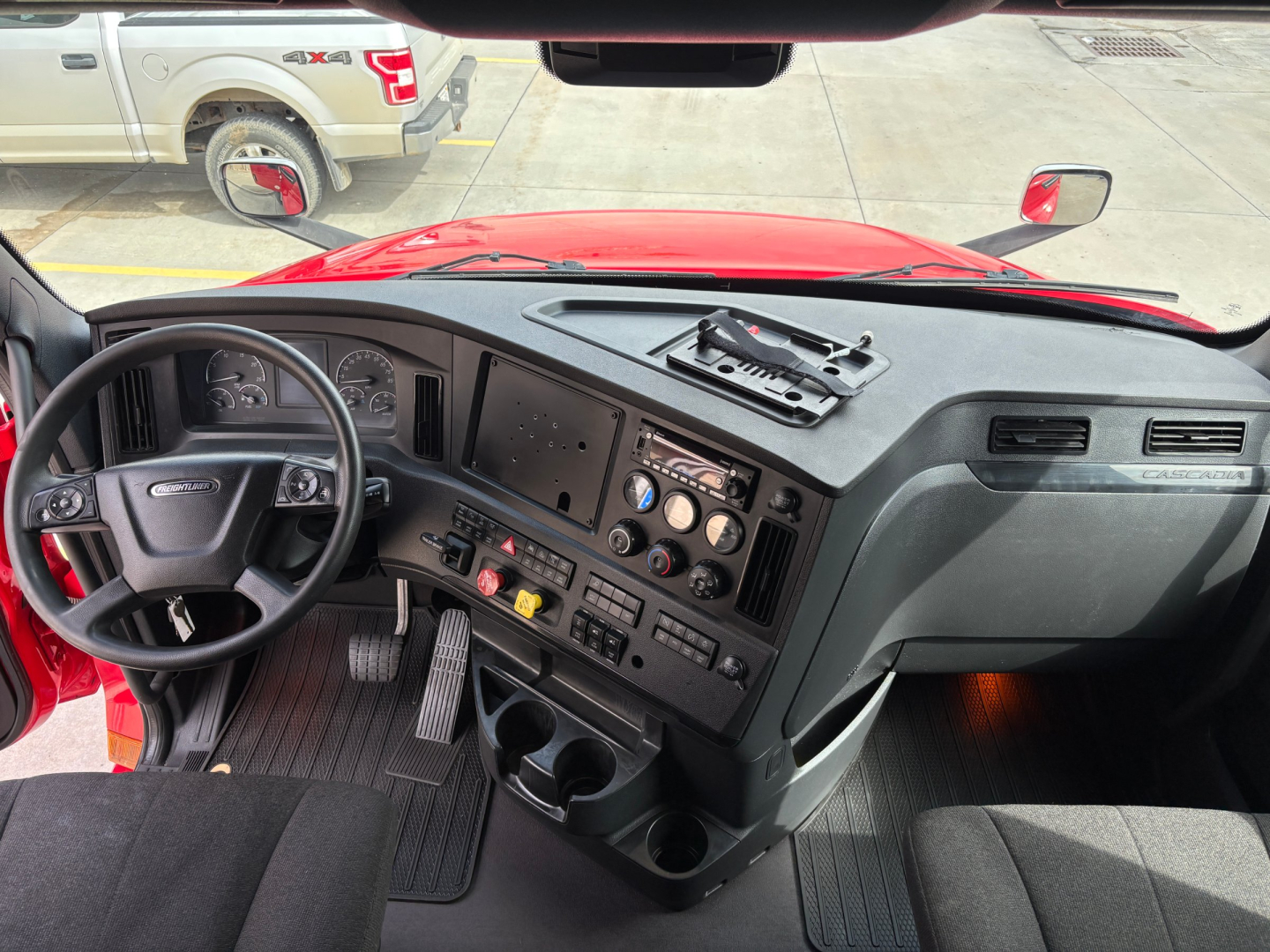 Truck cab interior showing steering wheel, dashboard, control panels, gauges, and center console in a Freightliner PT126064ST.