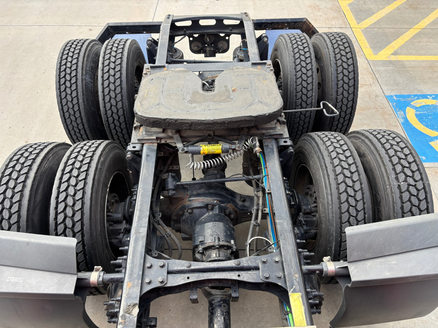 Chassis view of a Freightliner truck undercarriage showing rear axle with multiple dual tires and drive shaft components.