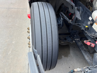 Front axle with dual tires and wheel assembly of a Freightliner PT126064ST showing tire tread and chassis components.