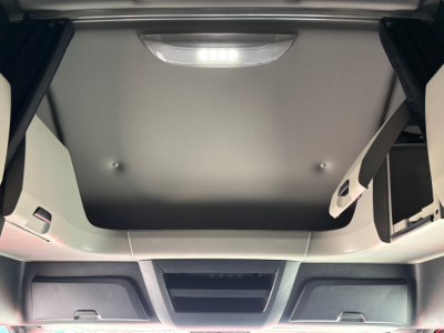 Cab interior roof hatch area of a Freightliner truck sleeper cab showing overhead storage and interior lighting.