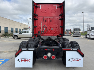 Rear view of Freightliner PT126064ST tractor showing fifth-wheel area and dual rear axles with quad tires, red cab back panel, and white MHC mud flaps.