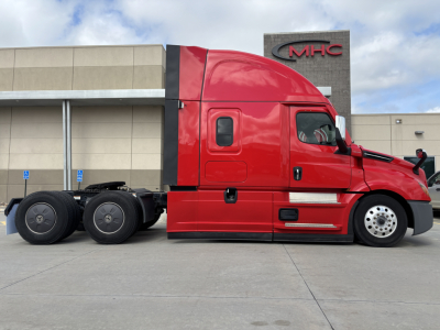 Freightliner PT126064ST sleeper tractor in red with extended cab and dual rear axles, side view showing wheel arrangement and cab details.