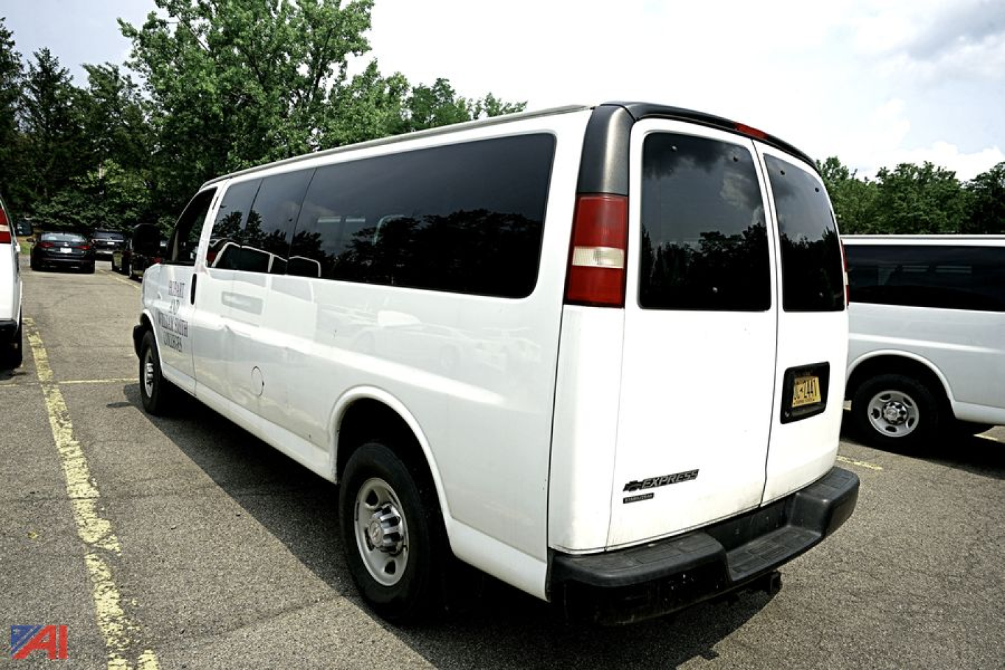 Chevrolet Express passenger van rear view showing extended body, white paint, tinted windows, and rear door; 12-passenger Ext. Suburban style used vehicle.