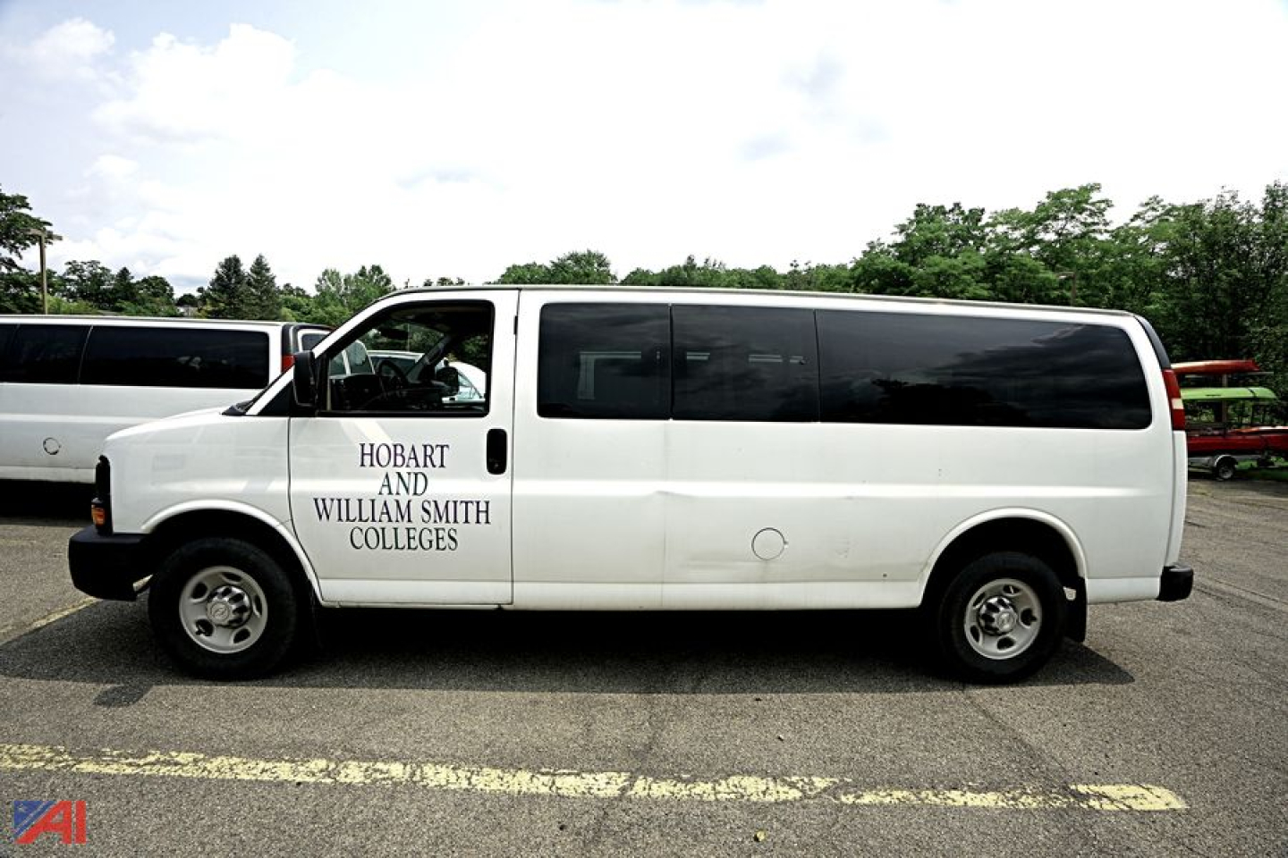 White 2015 Chevrolet Express passenger van side view showing Hobart and William Smith Colleges logo.