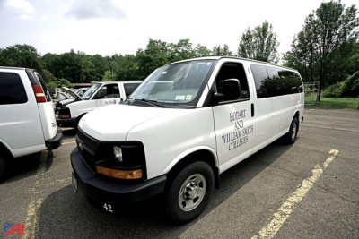 Chevrolet Express passenger van with Hobart and Williams College branding in a parking lot, front three-quarter view.