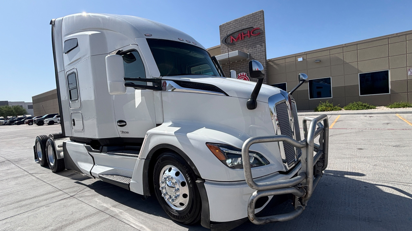 Kenworth T680 sleeper cab truck showing front grille guard and chrome bumper in a dealership lot