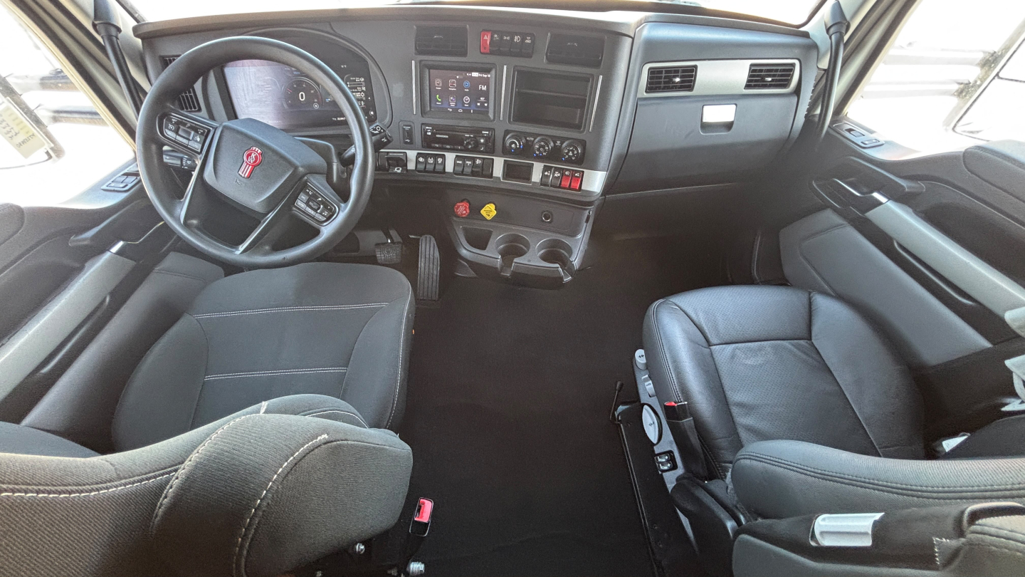 Kenworth T680 truck interior view showing steering wheel, dashboard, center console, and two front seats.