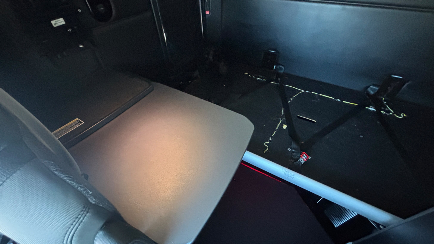 Interior of a 2023 Kenworth T680 sleeper cab showing seating area and cargo straps.