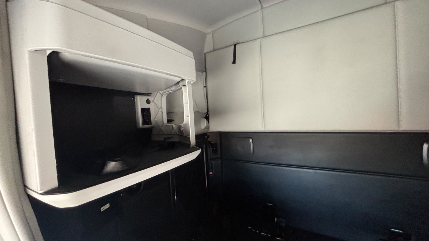Kenworth T680 sleeper cab interior with storage cabinet and control panel area visible