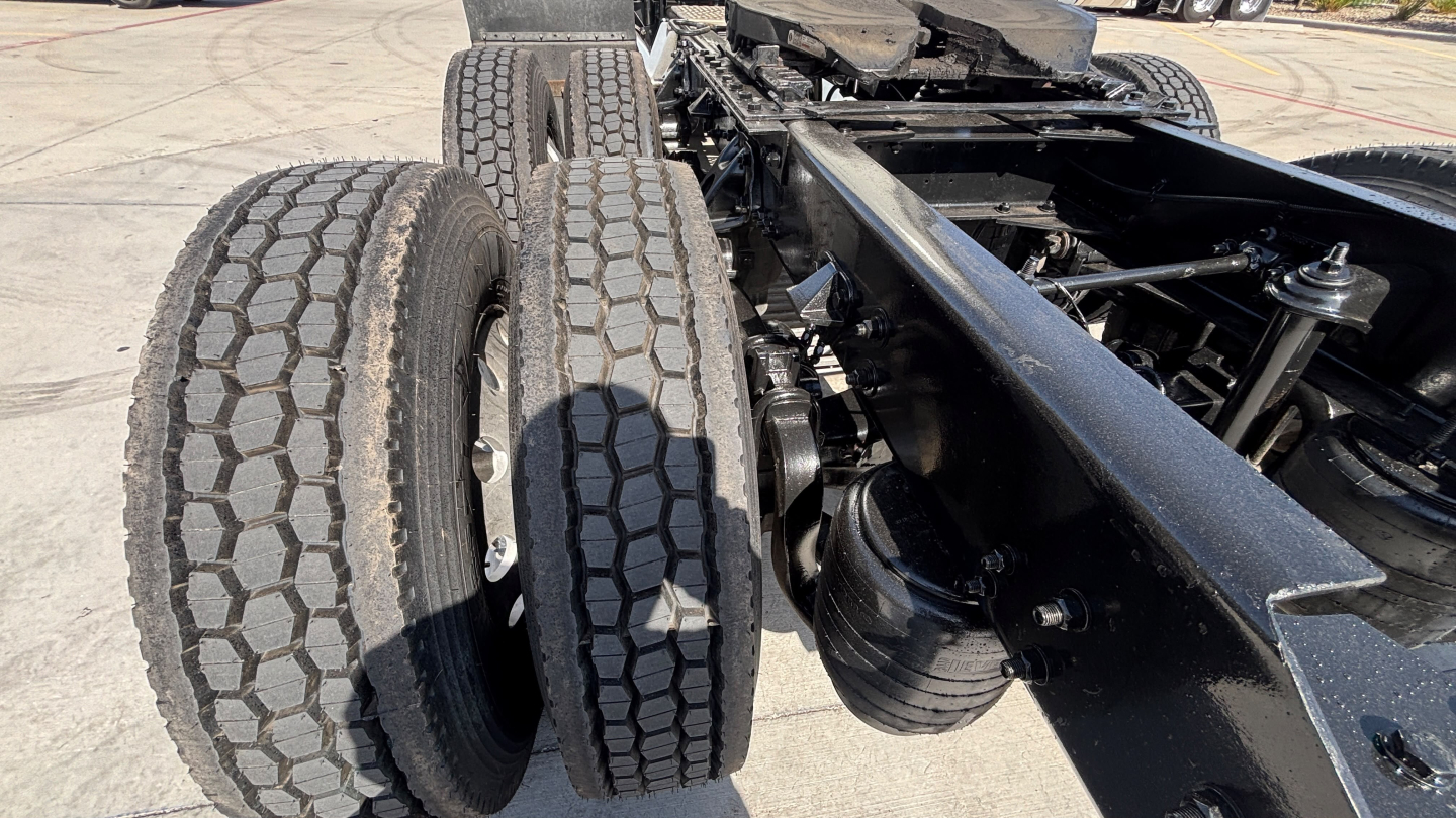 Dual rear truck wheels and chassis showing tires and suspension components on a Kenworth T680, with visible hexagonal tread pattern.
