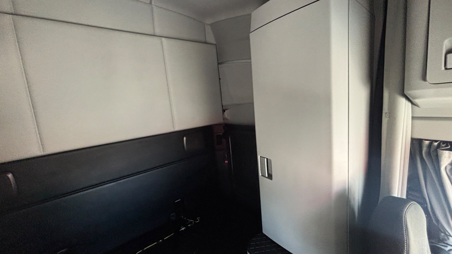 Kenworth T680 sleeper cab interior showing storage cabinet and seat with light gray panels.
