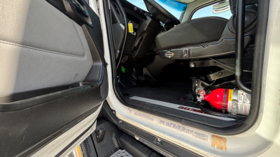 Kenworth T680 cabin entry showing interior and a red fire extinguisher mounted under the dashboard area.