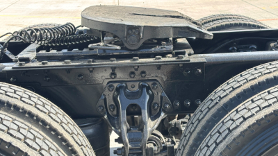 Kenworth truck chassis view showing fifth wheel and suspension at rear, dual rear wheels and drivetrain components