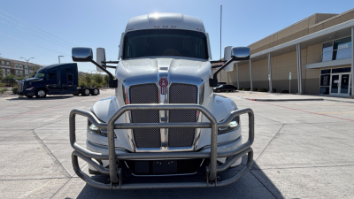 Kenworth T680 conventional sleeper truck front view with grille guard and chrome mirrors, silver exterior.