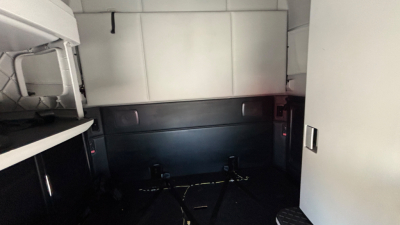 Truck cab interior showing sleeping area with storage cabinets and a mounting area for a bunk bed.