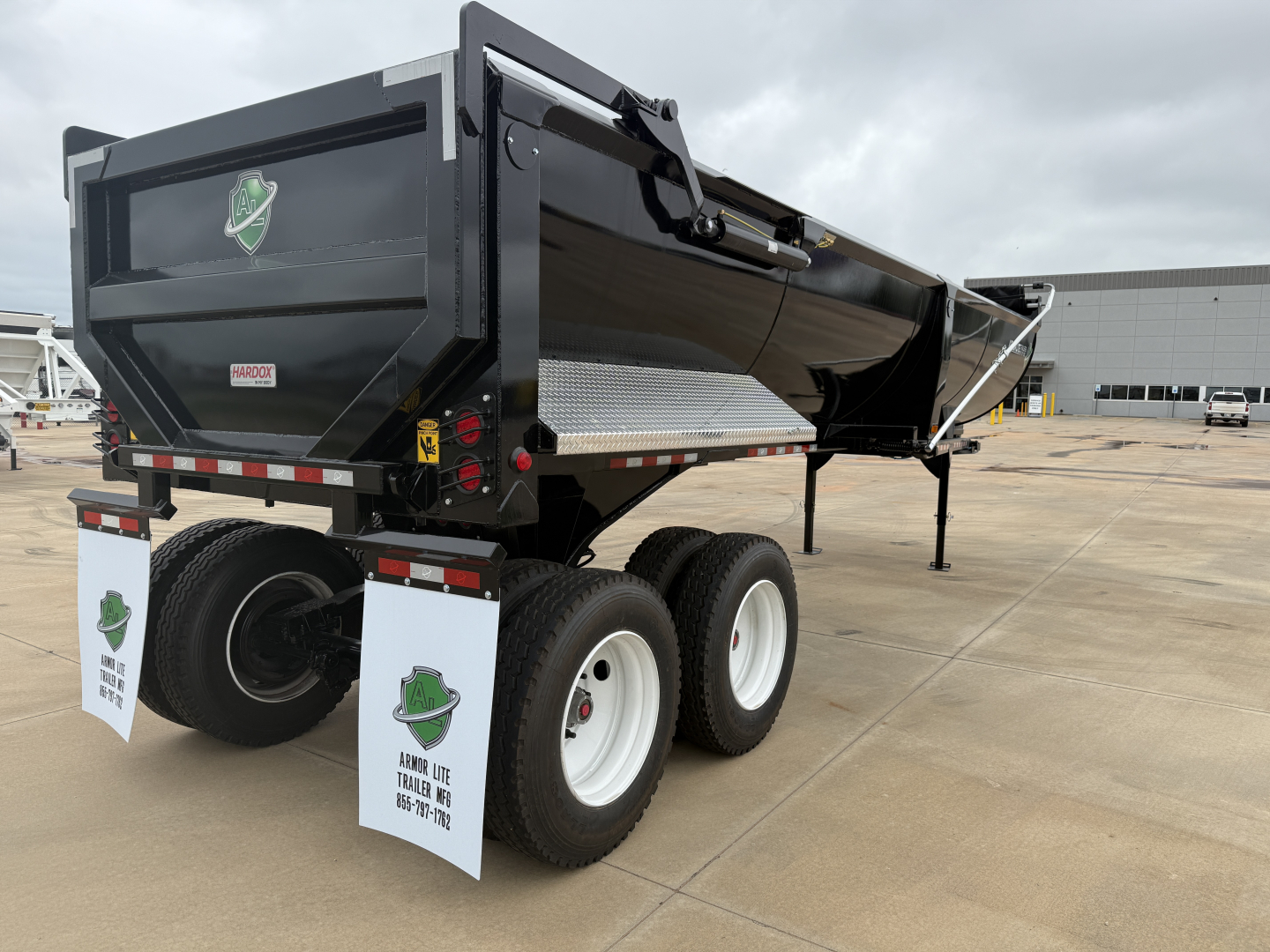 Dump trailer rear view showing Armor Lite SHD32/48 with black dump body, dual rear axle, white wheel wells, and PPE mudflaps.