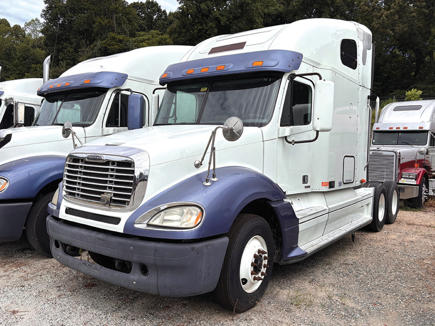 Truck cab exterior of a 2012 Freightliner CL120 Columbia with white and blue colors, sleeper bunk, dual rear wheels, chrome grille, and orange clearance lights.