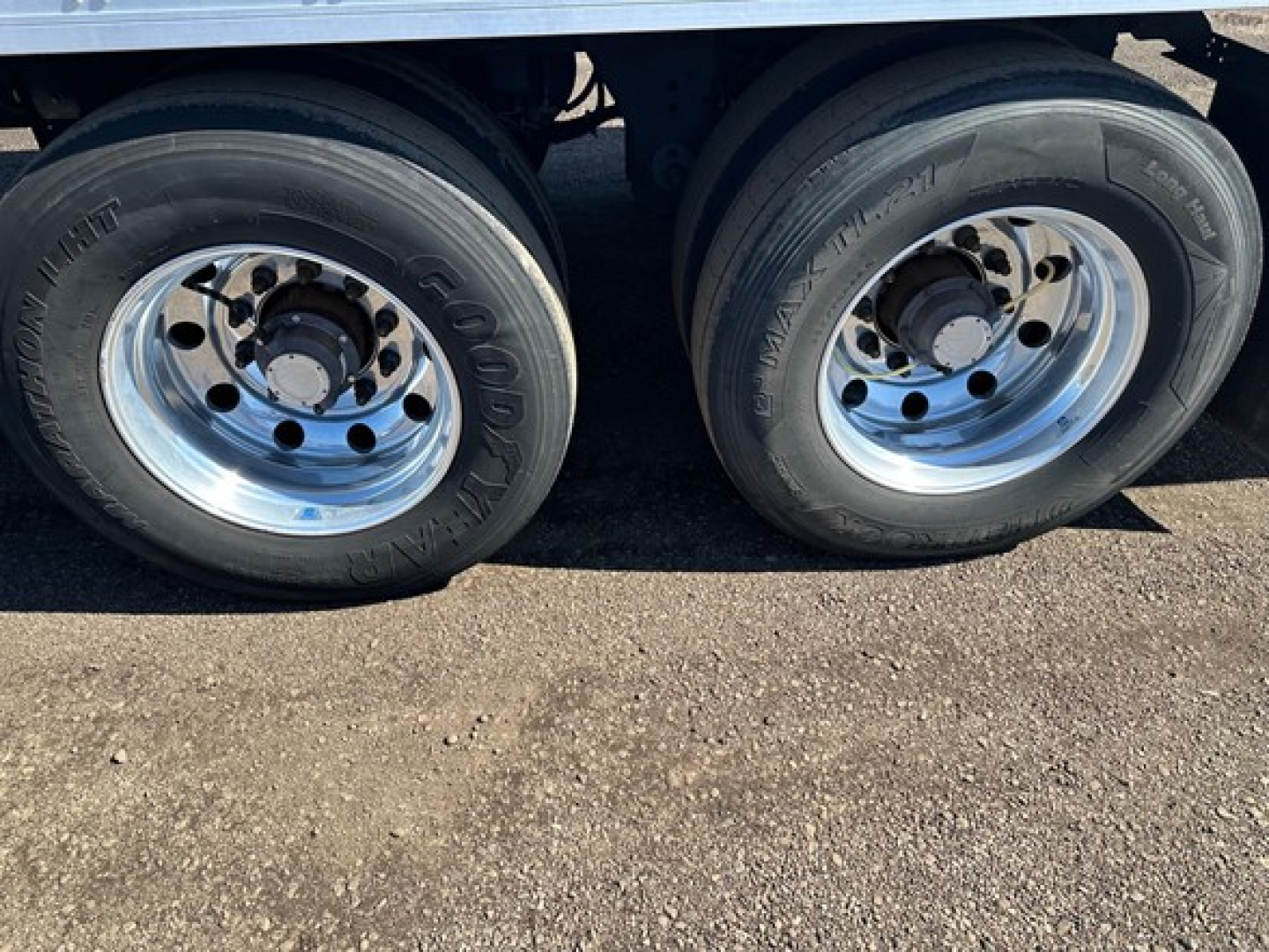 Dual tandem trailer wheels showing Goodyear tires and polished steel rims beneath a reefer trailer.
