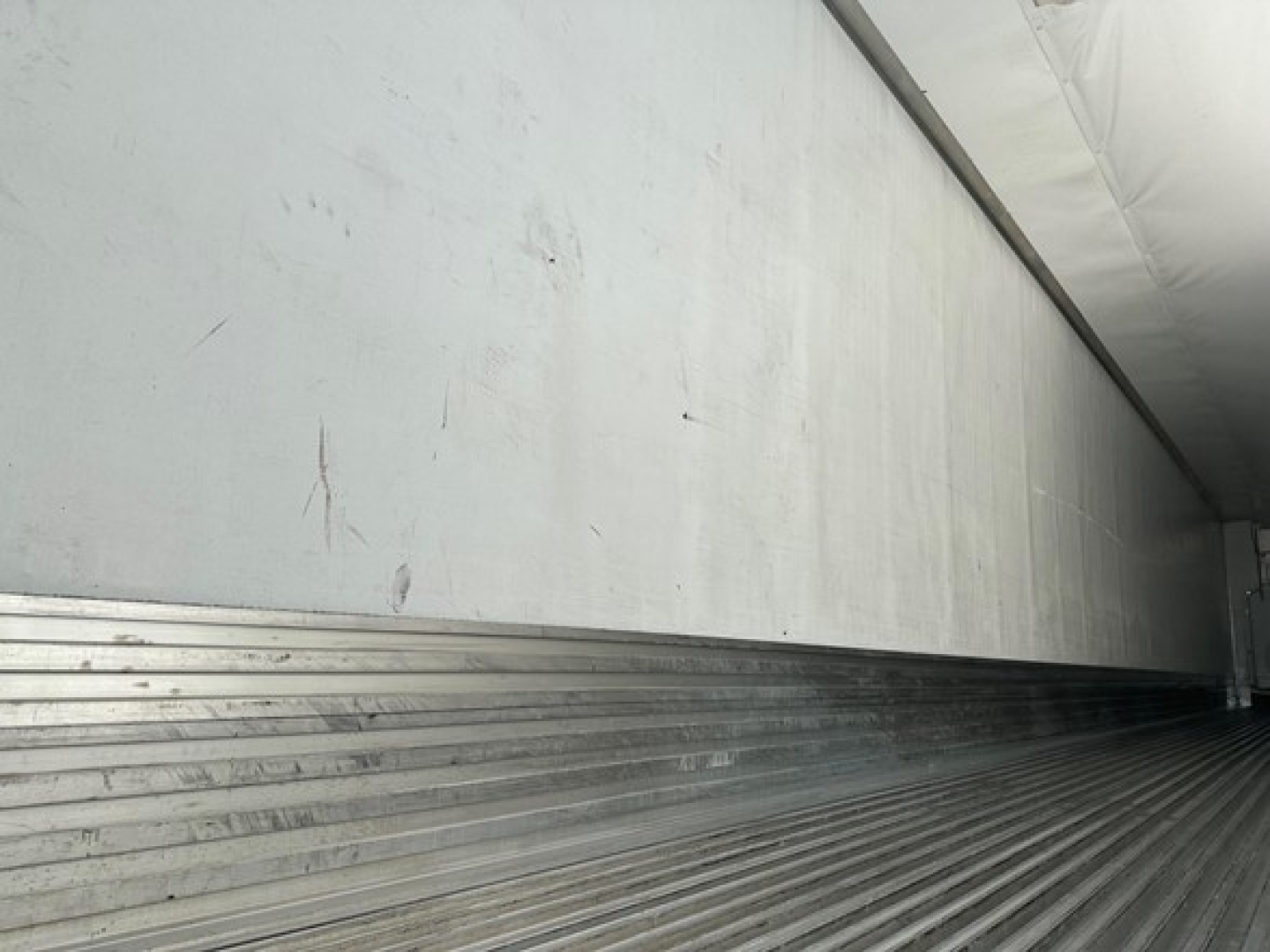 Trailer interior showing ribbed metal side wall and floor with a white upper panel.