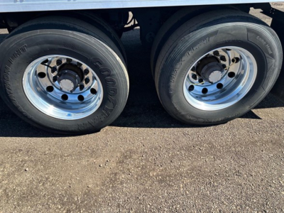 Dual tandem trailer wheels showing Goodyear tires and polished steel rims beneath a reefer trailer.