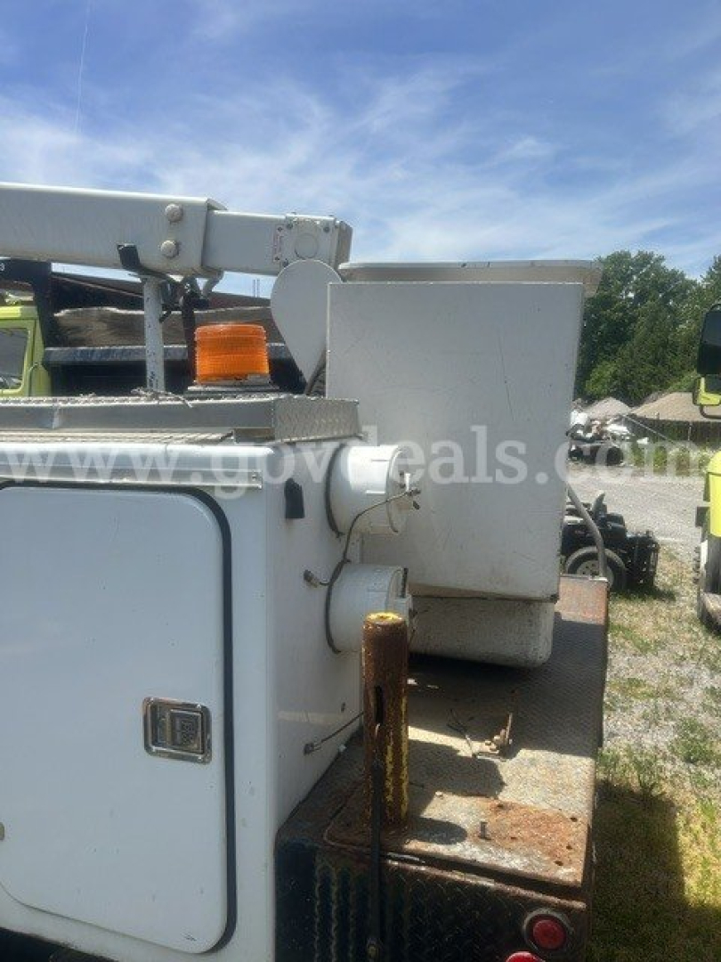 Back-right side of a truck-mounted utility body showing storage compartment door and rusted surface on the bed.
