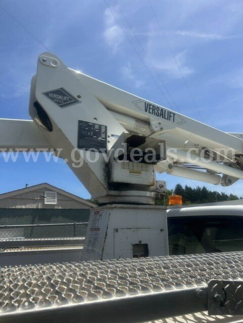 Versalift boom lift mounted on a truck truck bed with label VersaLift and operator controls visible.