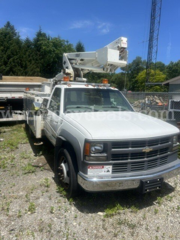 2000 Chevrolet C/K 3500 bucket truck with an elevated utility bucket on the bed; truck is white with a chrome bumper, precautions labels on the front lower panel, and a hydraulic boom mounted on the frame.