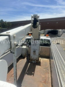 View of a utility bucket truck arm and platform on a Chevrolet C/K 3500; metal components, hydraulic boom, rust-colored deck surface, and safety rails visible.