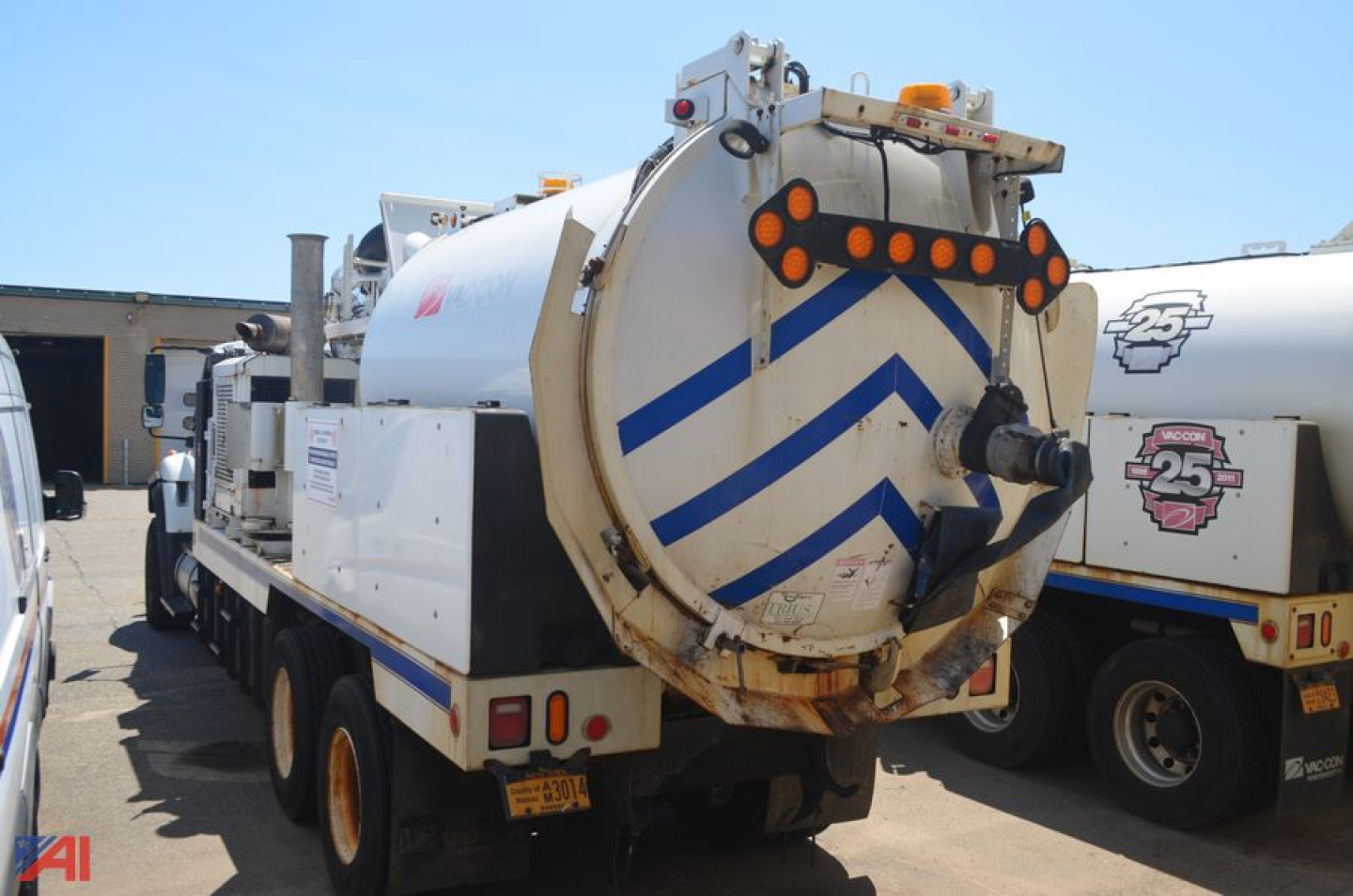 Vacuum truck rear view showing circular vacuum tank with blue chevron pattern and warning lights on top.