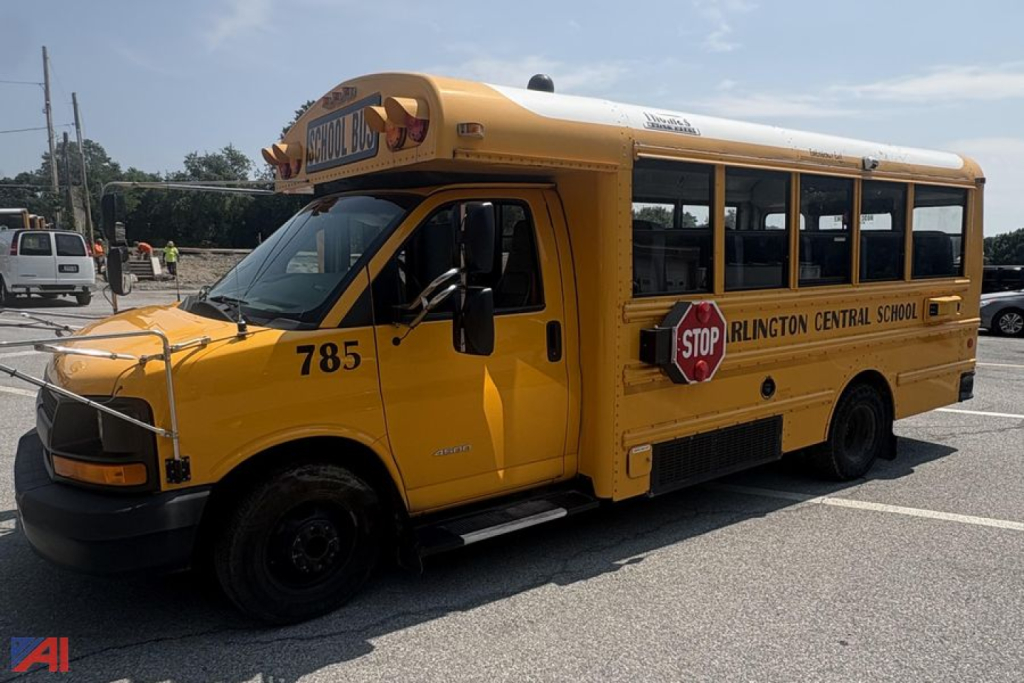 Mini school bus in yellow with “ Arlington Central School ” on side, number 785, stop sign, bus roof, front grille view