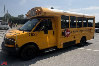 Mini school bus in yellow with “ Arlington Central School ” on side, number 785, stop sign, bus roof, front grille view