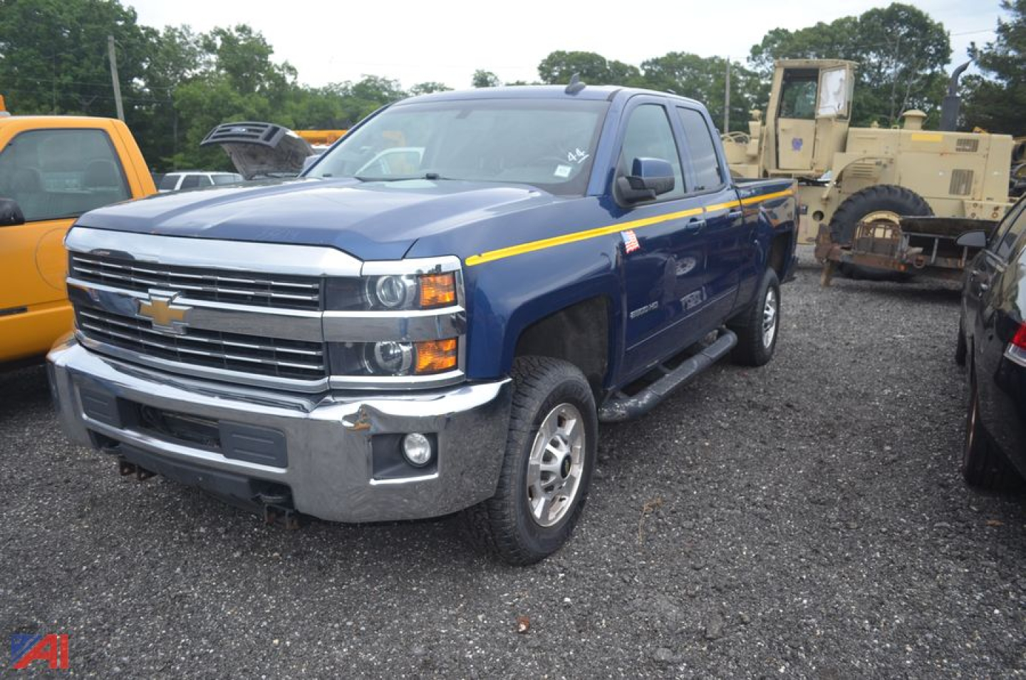 Chevrolet Silverado 2500HD pickup truck in blue with yellow stripe, front view, in a gravel lot.